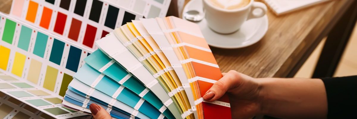 projektant trzyma w dłoniach wzornik kolorów i dobiera kolory w marketingu